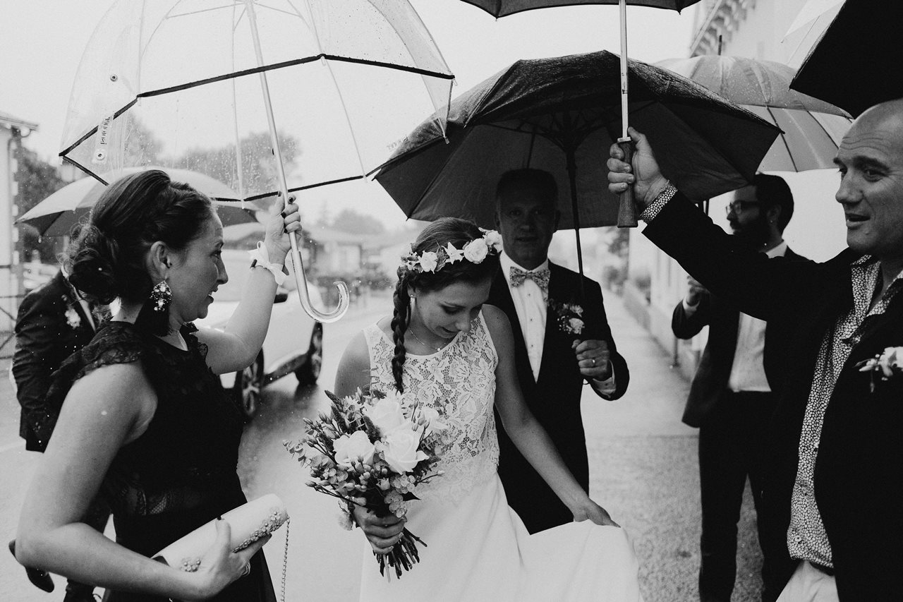 Photo mariage arrivée mariée mairie parapluies noir et blanc
