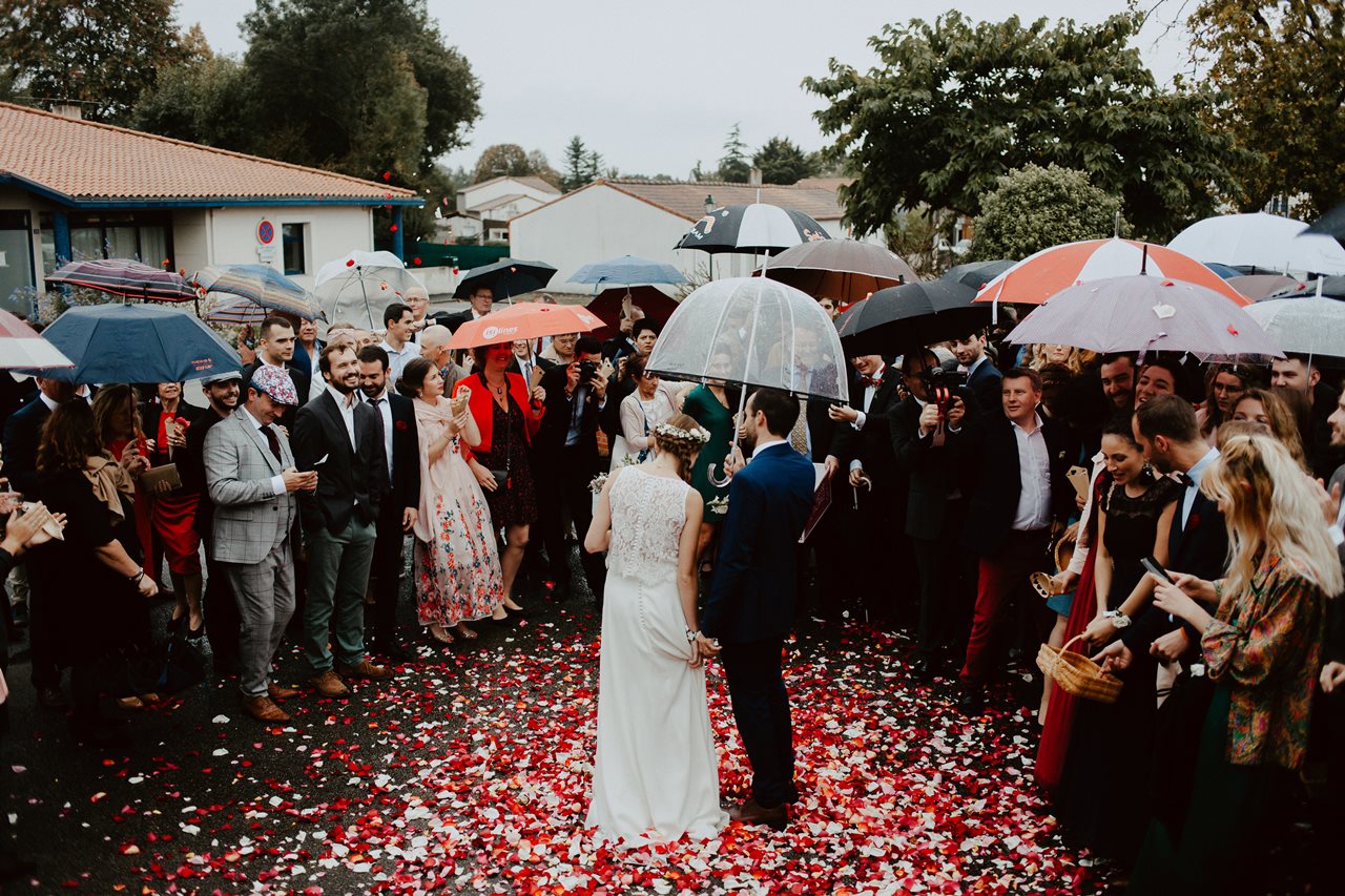Photo mariage sortie marie mariés invités parapluies