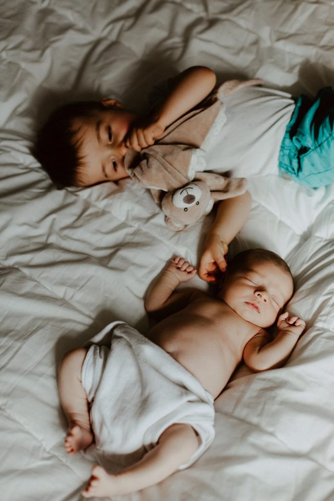 séance nouveau-né lifestyle portrait frère et soeur lit calin doudou